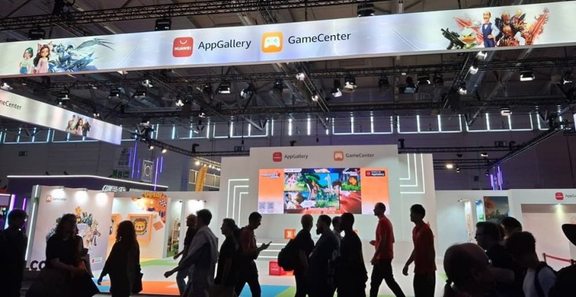 A large booth on a convention center floor topped with a banner showing the Huawei AppGallery logo and famous mobile characters.