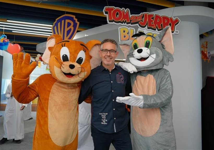 A picture of a man between two mascots dressed as Tom and Jerry respectively