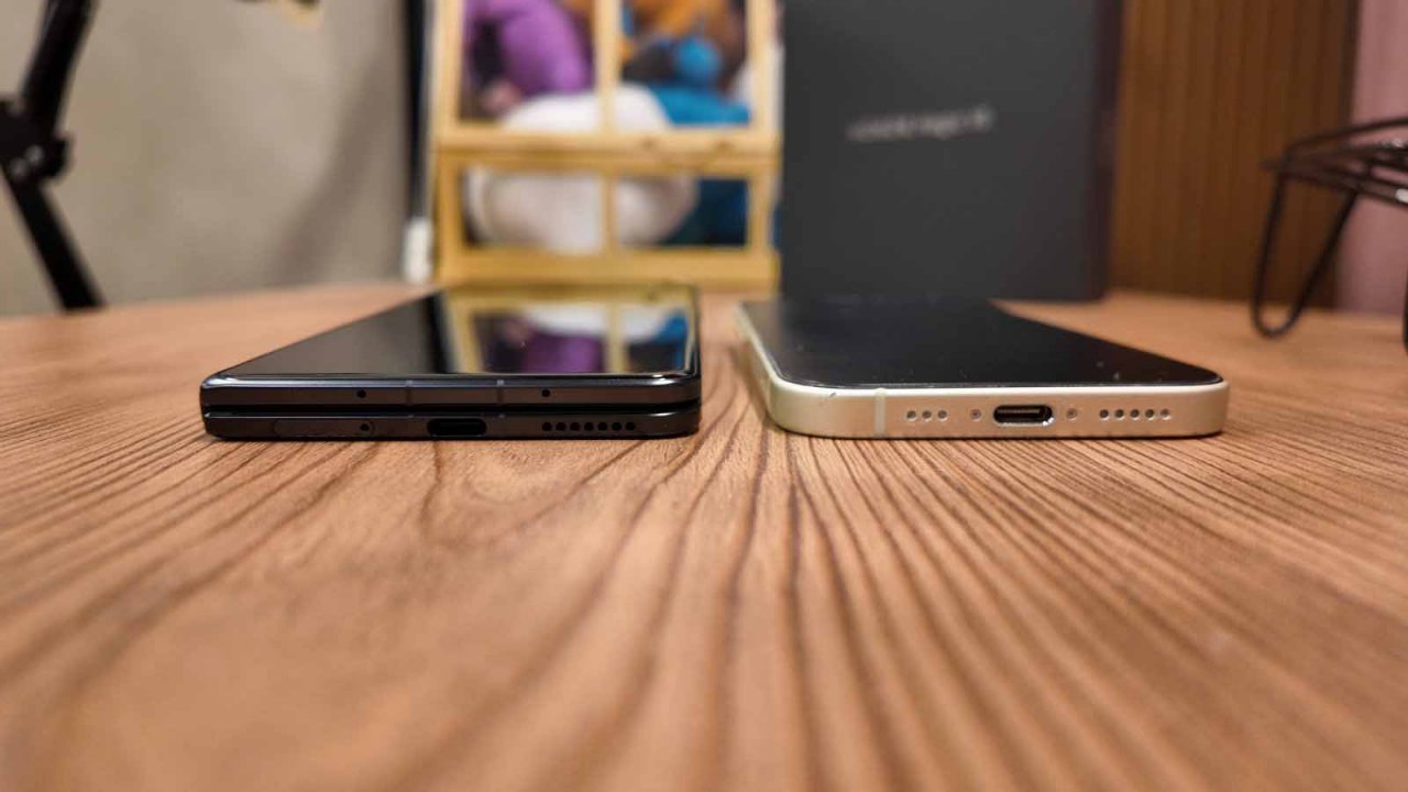 the honor magic v5 laid on a table beside an iphone 15