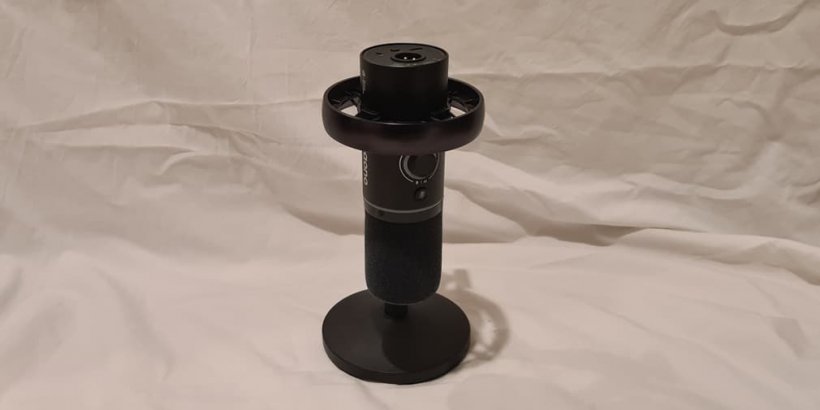 A front-on view of a microphone tilted on a small stand on a white background, there is a visible dial on the side.