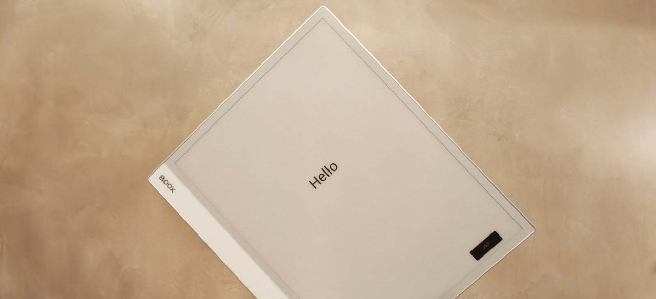 an e ink device held up against a wall with the word hello on screen