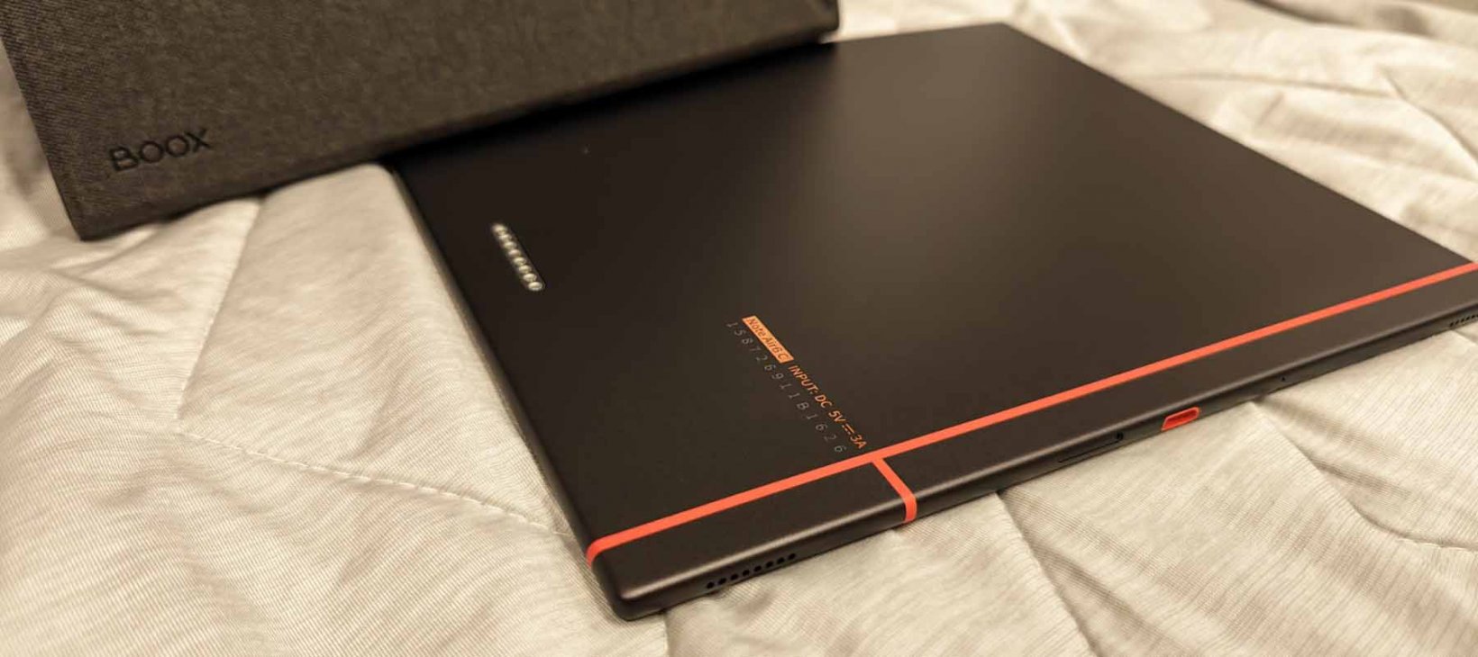 the boox note air6 c lying face down on a couch showing its red accent line