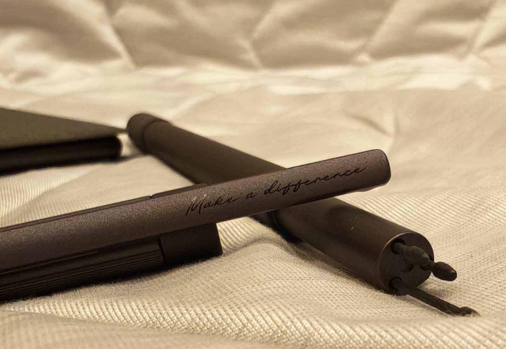 an uncapped stylus with make a difference etched on it